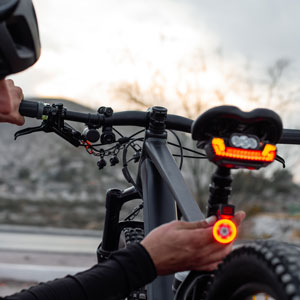 Woman attaching a tail light to the back of her bicycle, enhancing visibility and safety for night riding.