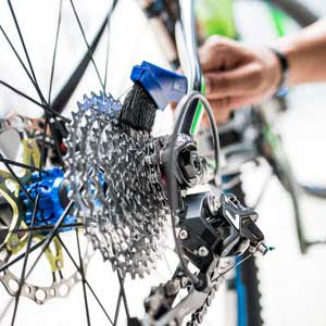 Man cleaning the drivetrain of a bicycle with a brush, removing dirt and grime for smoother performance.